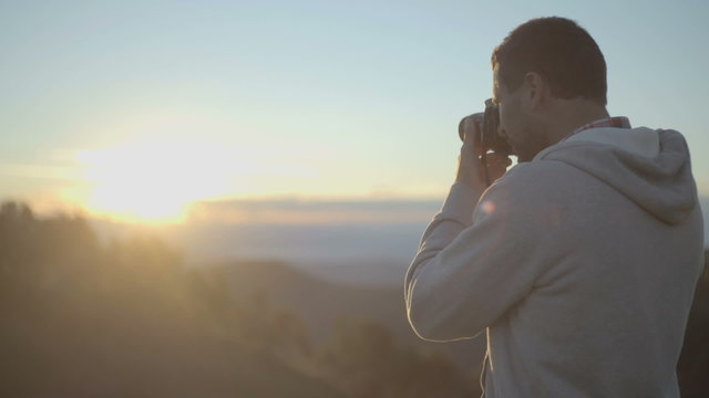 Man shoot photos with camera at sunrise or sunset   