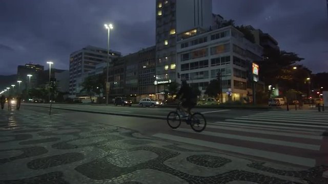 Slow panning shot from crosswalk down Copacabana street with biker.
