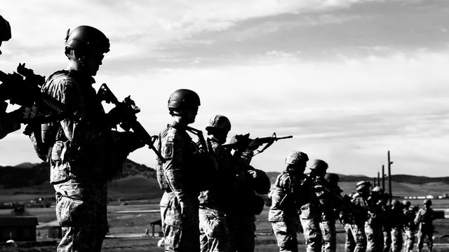 High contrast black and white shot of soldiers practicing firing technique.
