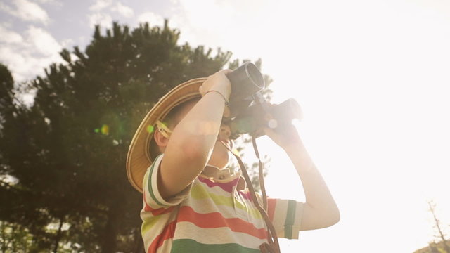 Child wearing pith helmet is playing with binoculars