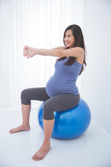 Beautiful asian pregnant woman doing exercise with a swiss ball,