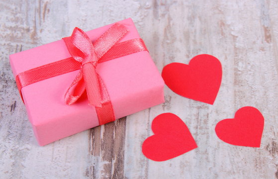Wrapped gift for birthday, valentine or other celebration and red hearts