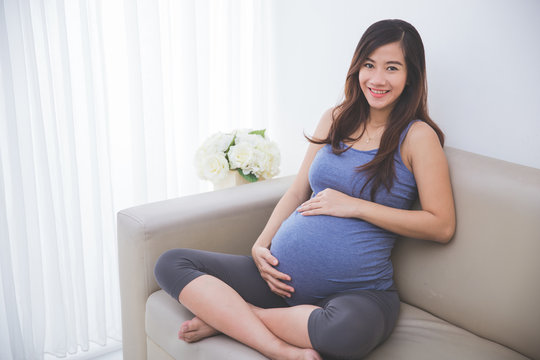 Beautiful pregnant woman smiling in to camera while sitting on t
