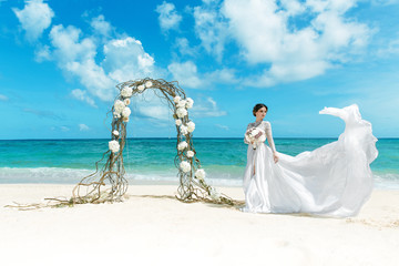 Fototapeta na wymiar Beautiful brunette fiancee in white wedding dress with big long