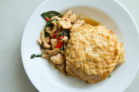 deep-fried egg toppen on stir fried chicken with basil leaf and