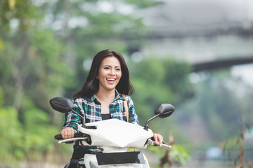Young asian woman riding a motorcycle in a park