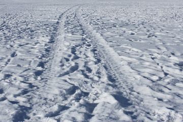 Fototapeta na wymiar Wheel track and human footprints on the snow