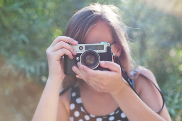Beautiful young girl taking pictures with a old vintage camera