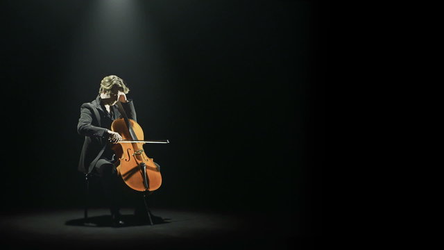 Cellist is tuning his cello alone on stage   
