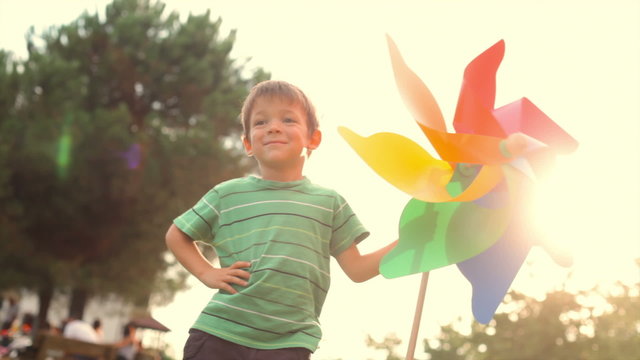 happy child play with colorful pinwheel at sunset park outdoor   