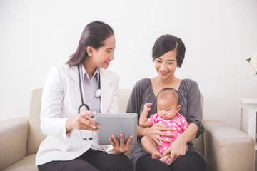 Asian female pediatrician showing something on tablet pc while a