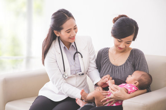 Asian female pediatrician examining a baby girl in the mother la