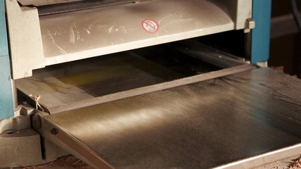 Joiner working on the planer in the carpentry workshop