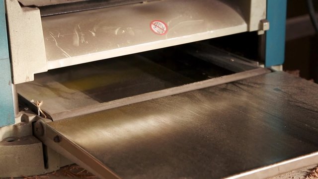 Joiner working on the planer in the carpentry workshop