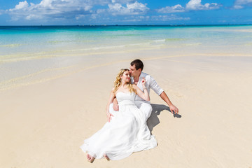 Fototapeta na wymiar Happy bride and groom having fun on a tropical beach. Wedding an