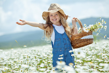 Happy little girl in a camomile field 