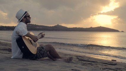 Man play guitar on beach at sunset slow motion - Powered by Adobe
