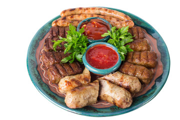 Plate of grilled sausages with red sauces.