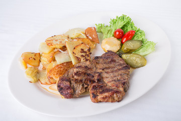 Grilled pork steak with pickles and garnish.