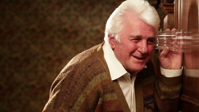 Senior man indoor close up is eavesdropping on neighbour   