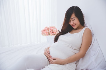 Beautiful pregnant woman smiling looking at her belly