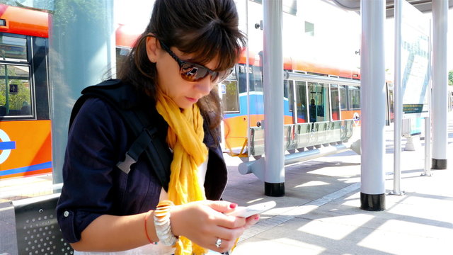 Woman using smart phone waiting in a railway train station