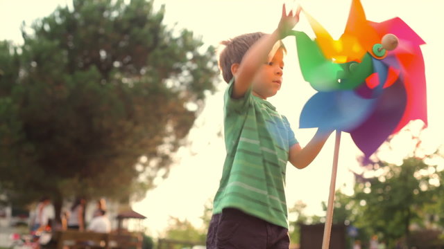 happy child play with colorful pinwheel at sunset park outdoor   