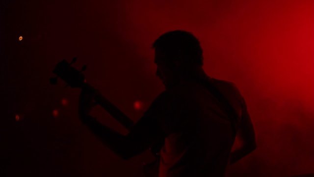 Bass player on the stage playing live with smoke