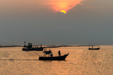 silhouette of fishermen with yellow and orange sun in the background