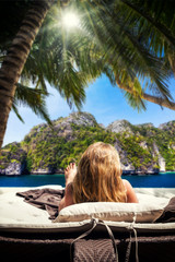 Fototapeta premium Woman relaxing on the wooden deck by the beach at resort