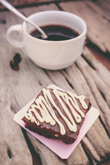 Cake chocolate brownie and hot coffee on old wooden background.