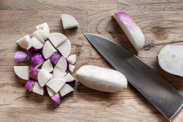 slices of fresh purple turnip on an oak cutting board with a kitchen knife