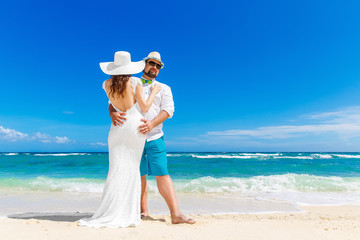 Fototapeta na wymiar Beautiful brunette bride in white wedding dress and straw hat an