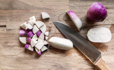 slices of fresh purple turnip on an oak cutting board with a kitchen knife