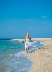 Fototapeta na wymiar Beautiful young bride walking on the beach