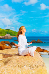 Young woman practices yoga on the rock