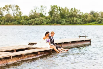 Foto op Canvas Beautiful bride with groom by a lake. Kiss and hug each other © satura_