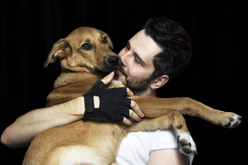 Portrait of a man hugging his lovely golden puppy on black backg