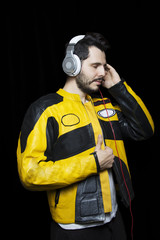 Young man in yellow leather jacket  listening to music with plea