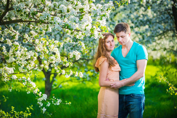 Young beautiful couple in love among apple trees