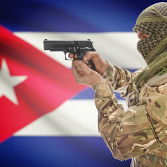 Fototapeta premium Male with gun in hands and national flag on background - Cuba
