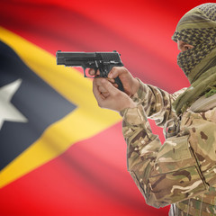 Fototapeta premium Male with gun in hands and national flag on background - East Timor