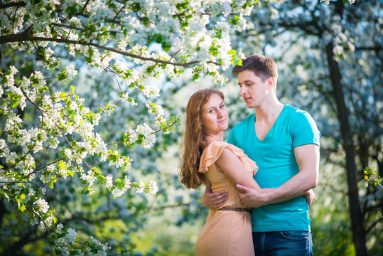 Young beautiful couple in love among apple trees