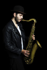 Fototapeta na wymiar A saxophone player in a hat in a dark background. Saxophone Play