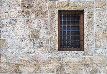 Window with bars in the old stone wall
