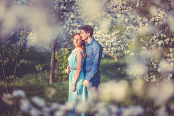 Young beautiful couple in love among apple trees