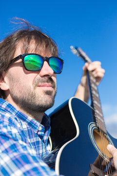 Bearded man in sunglasses playing guitar