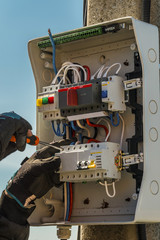 Hands of an electrician with screwdriver at an electrical control panel