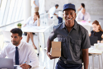 Portrait Of Courier Collecting Package From Busy Office