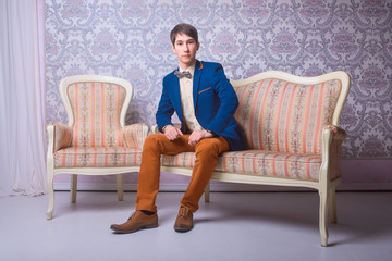 young man in classic suit is sitting on the couch